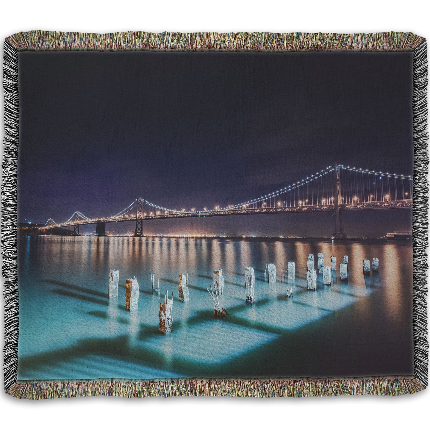 A woven throw blanket designed with a photo of the Oakland Bay Bridge in San Francisco at night, taken from the Embarcadero.