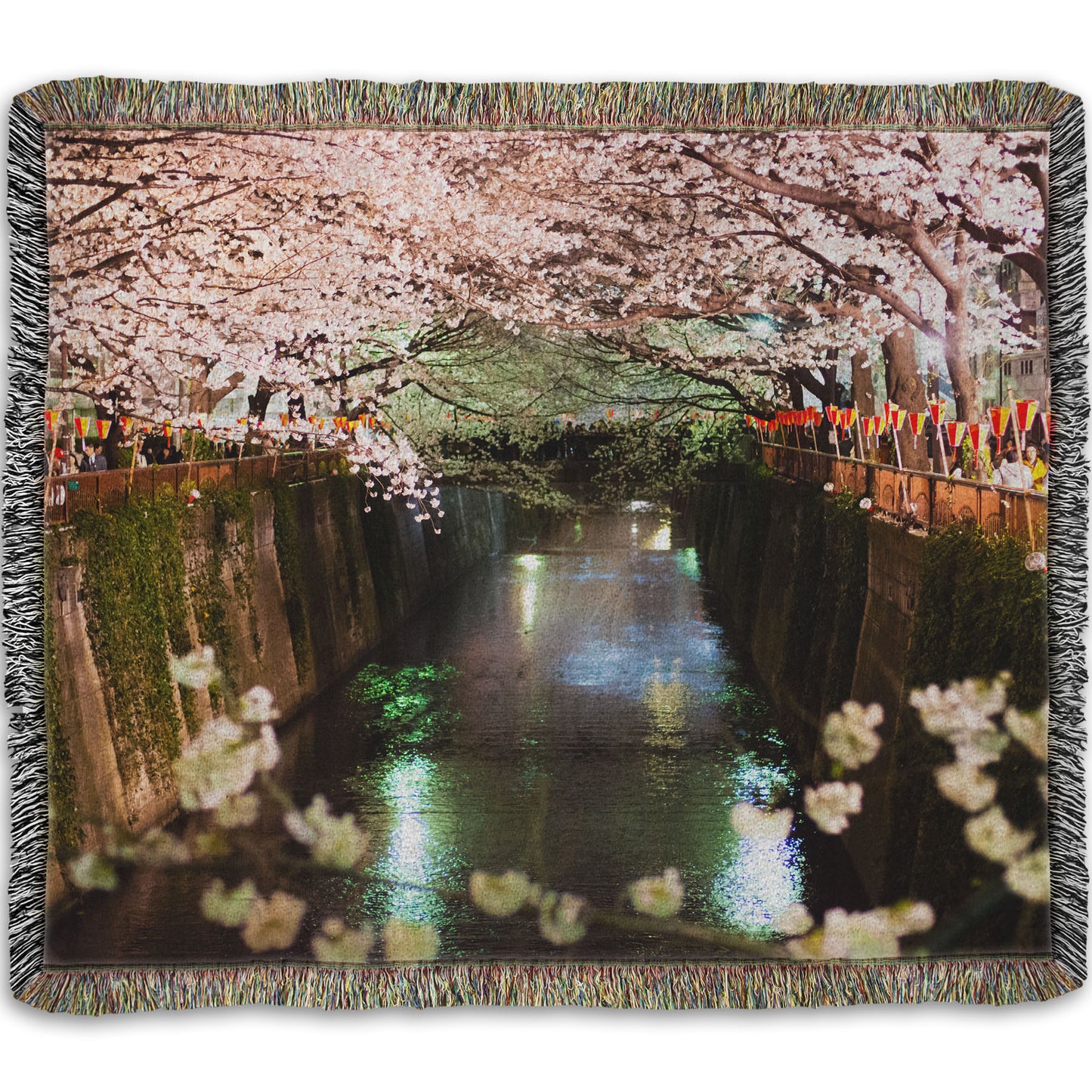 A woven throw blanket designed with a photo of cherry blossom trees over a canal at Meguro River in Tokyo, Japan.