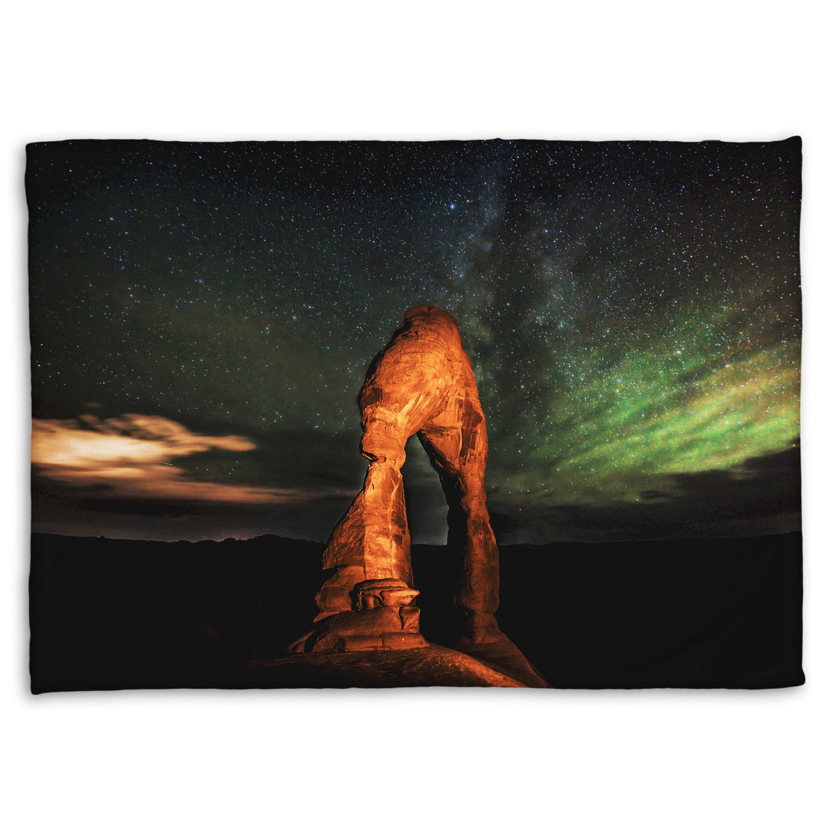 Coral fleece blanket designed with a nighttime photo of Delicate Arch in Arches National Park, Utah. The arch is lit with staged lighting, with a backdrop of a starry night sky.