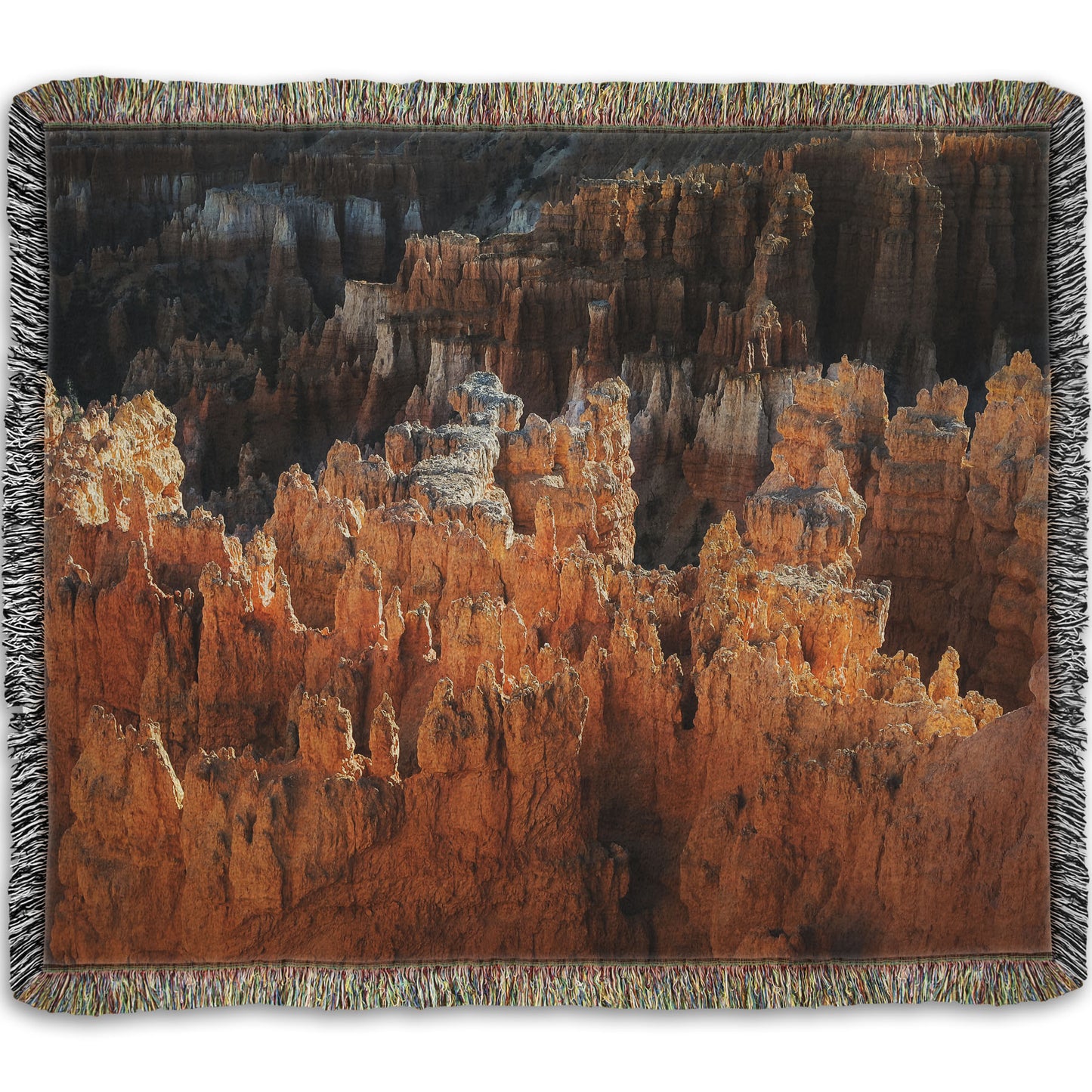 A woven blanket designed with a photo of hoodoo rock formations, jagged stone spires formed by the erosion of a plateau, in Bryce Canyon National Park from a high angle.