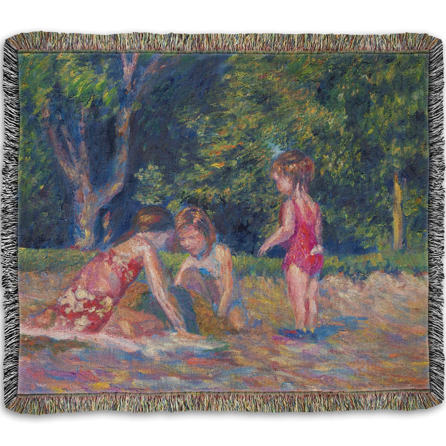 A woven blanket designed with a painting of three children playing in the sand at a beach. Their red swimsuits contrast the green foliage in the background.