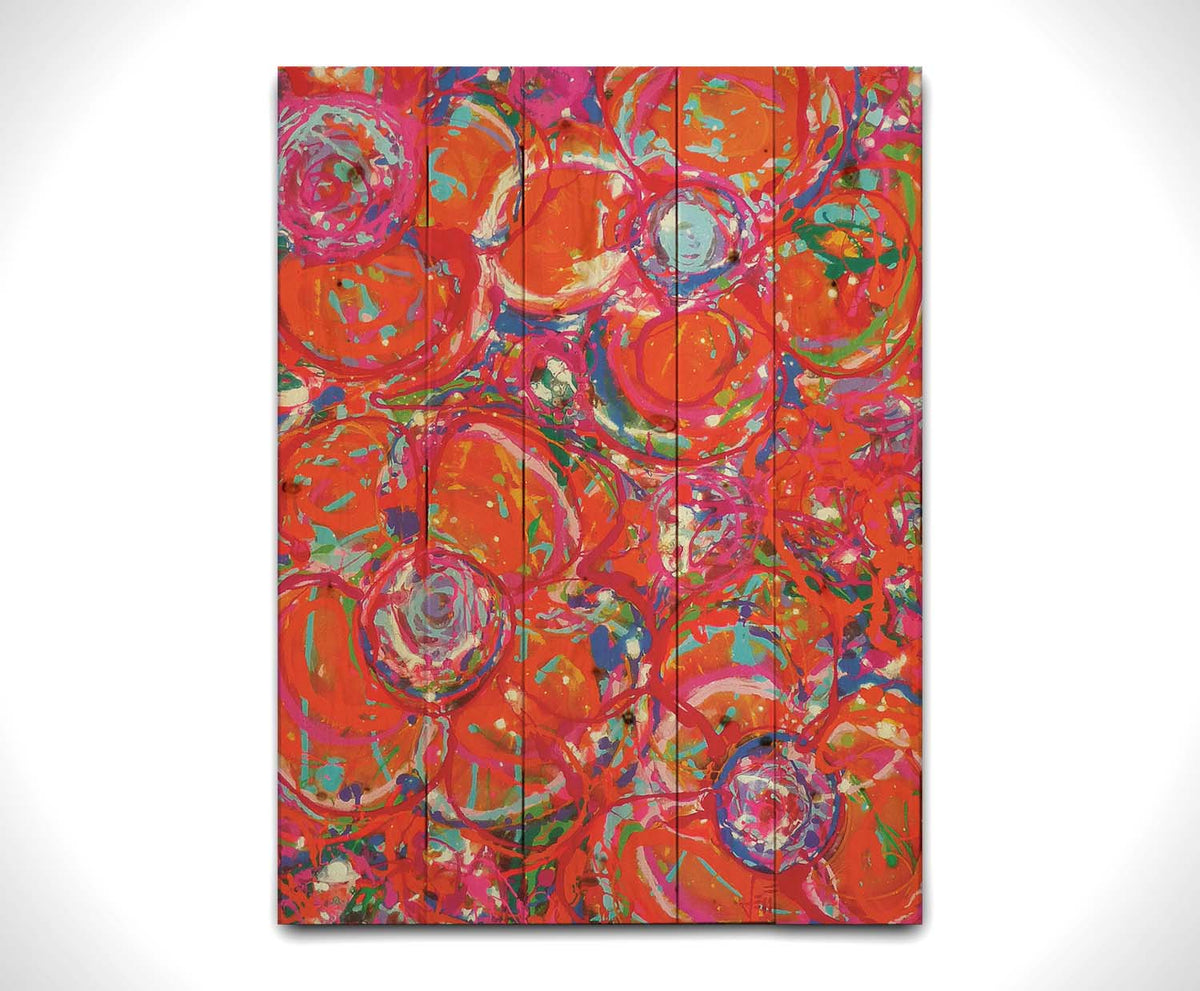 A drip painting of a cluster of abstracted flowers created with splatters of orange, red, and pink with accents of green, blue, yellow, and purple. Printed on a wood pallet.