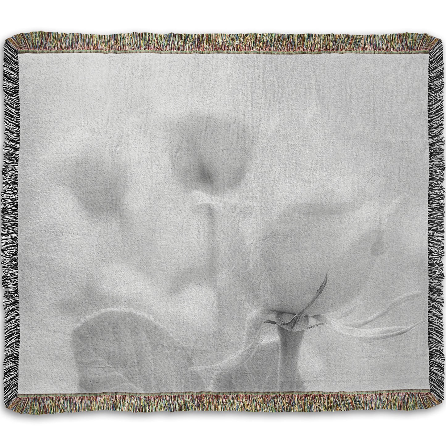 A woven throw blanket designed with a grayscale photo of three roses bathed in a soft white light.