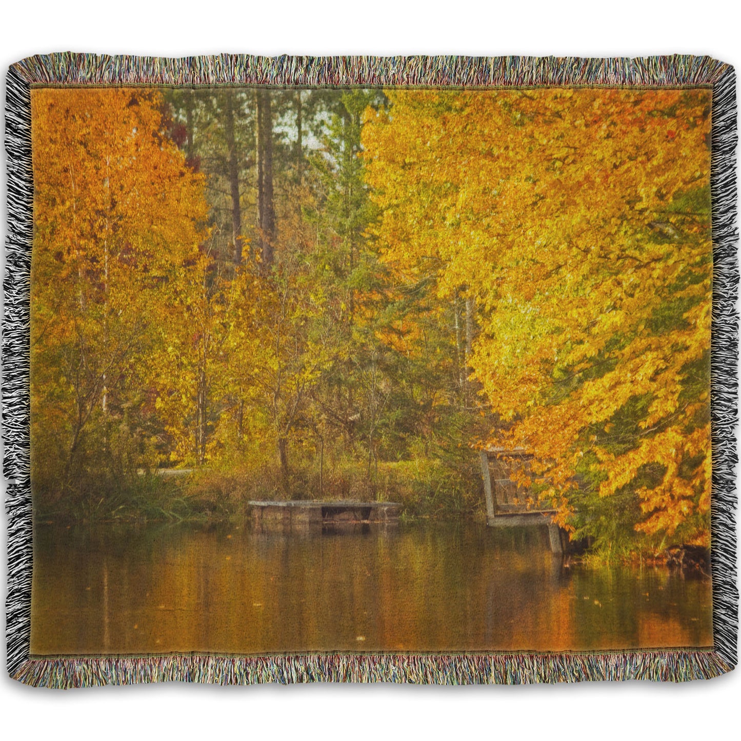 A woven throw blanket designed with a photo of yellow autumn trees at a pond, their leaves reflecting off the water.
