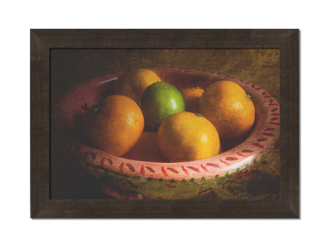 A photo of a bowl of oranges, with one lime placed in the center. Printed on canvas and framed.
