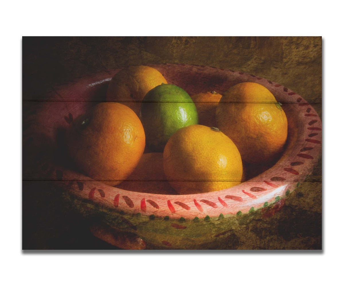 A photo of a bowl of oranges, with one lime placed in the center. Printed on a box board.