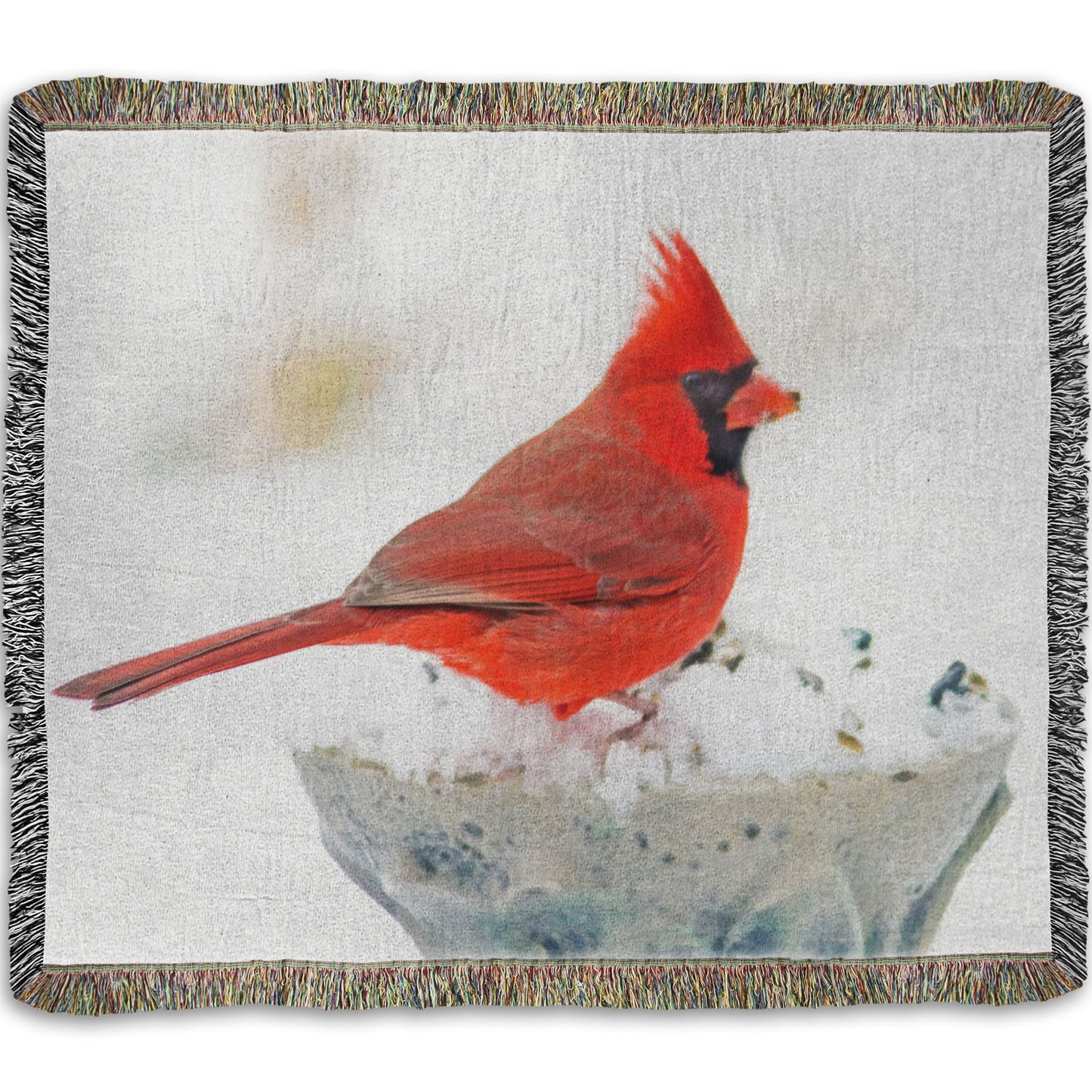 A woven throw blanket printed with a photograph of a red cardinal against white snow.