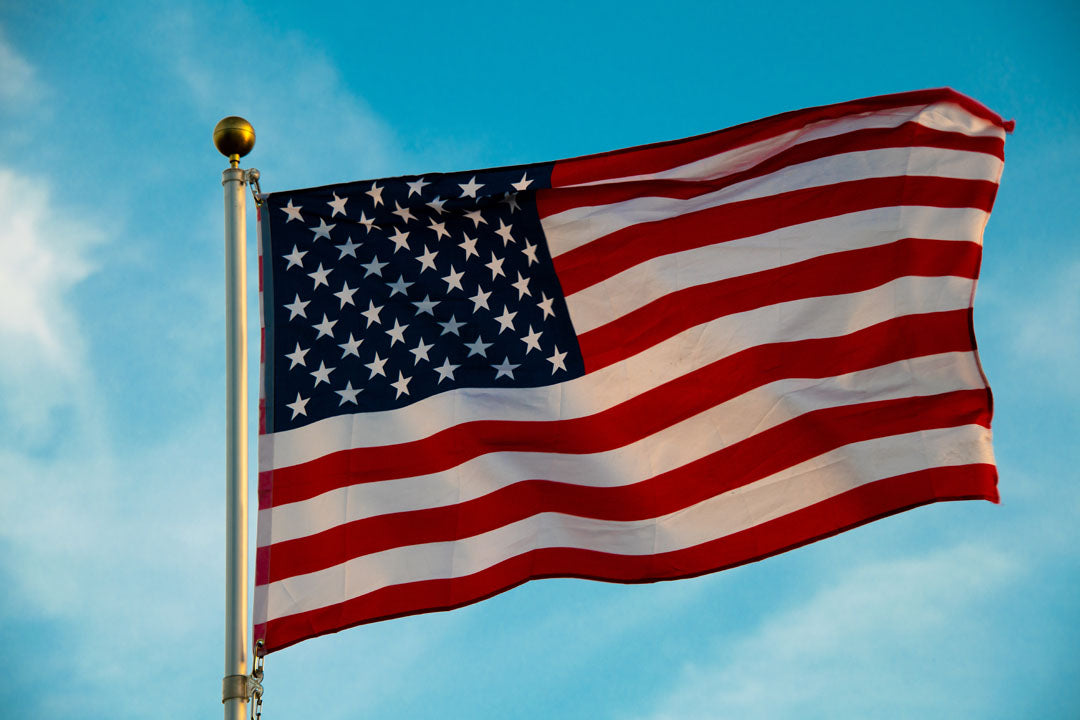 A photo of an American flag against a bright blue sky.