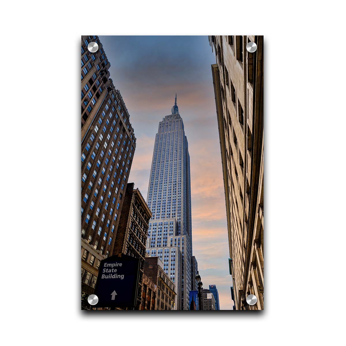 A photograph looking up at the Empire State Building in New York against a blue sky and orange clouds. Printed on acrylic.