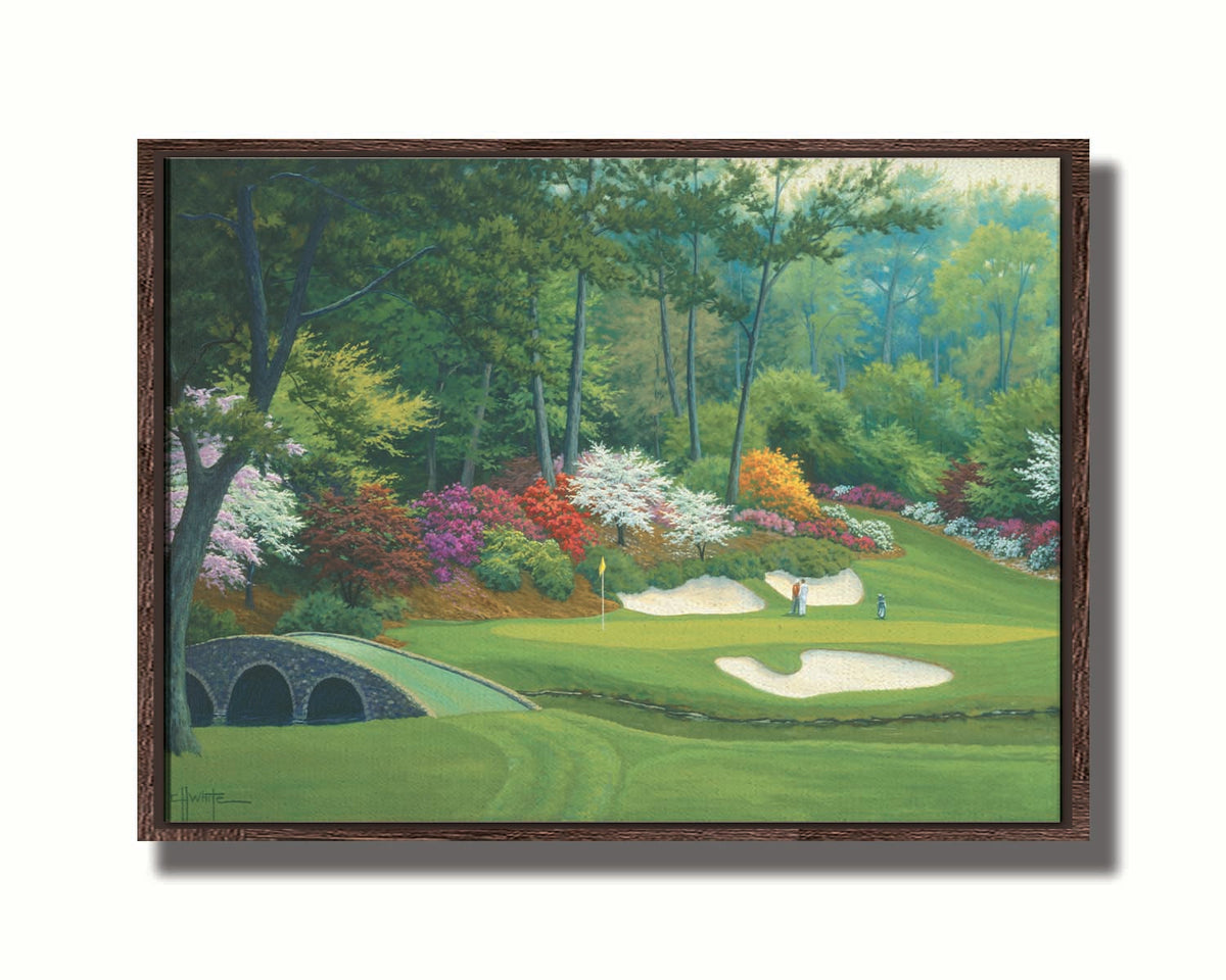 A painting of the Augusta Nationals golf course in Georgia. The course is encircled by foliage and flowers of all colors, and a bridged stream runs through the center. A few golfers stand near a small sand pit, lining up a shot to the nearby hole. Printed on canvas in a float frame.