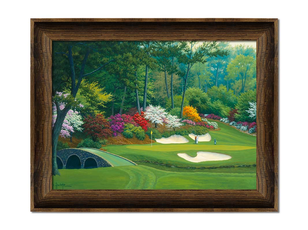 A painting of the Augusta Nationals golf course in Georgia. The course is encircled by foliage and flowers of all colors, and a bridged stream runs through the center. A few golfers stand near a small sand pit, lining up a shot to the nearby hole. Printed on canvas and framed.