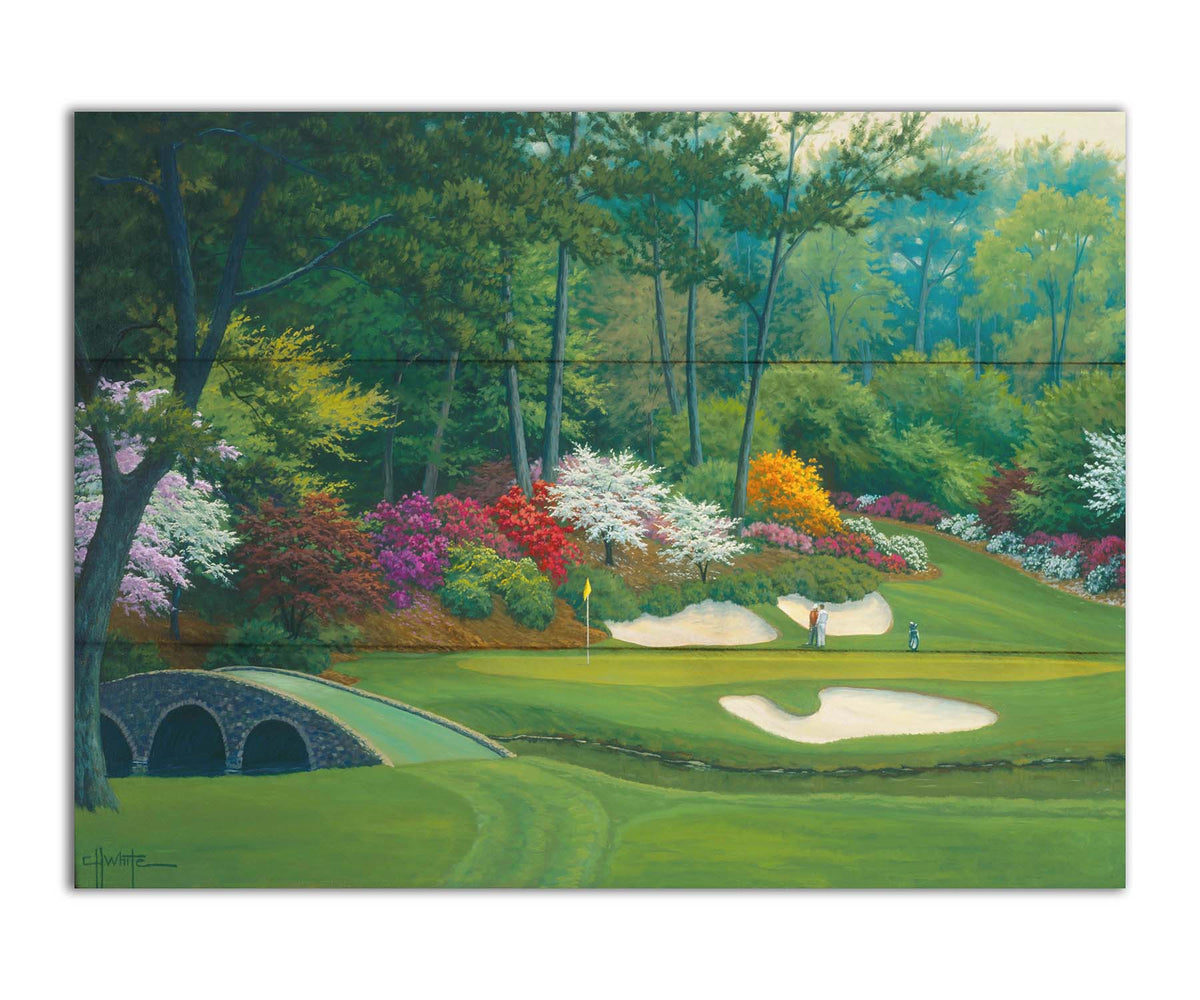 A painting of the Augusta Nationals golf course in Georgia. The course is encircled by foliage and flowers of all colors, and a bridged stream runs through the center. A few golfers stand near a small sand pit, lining up a shot to the nearby hole. Printed on a box board.