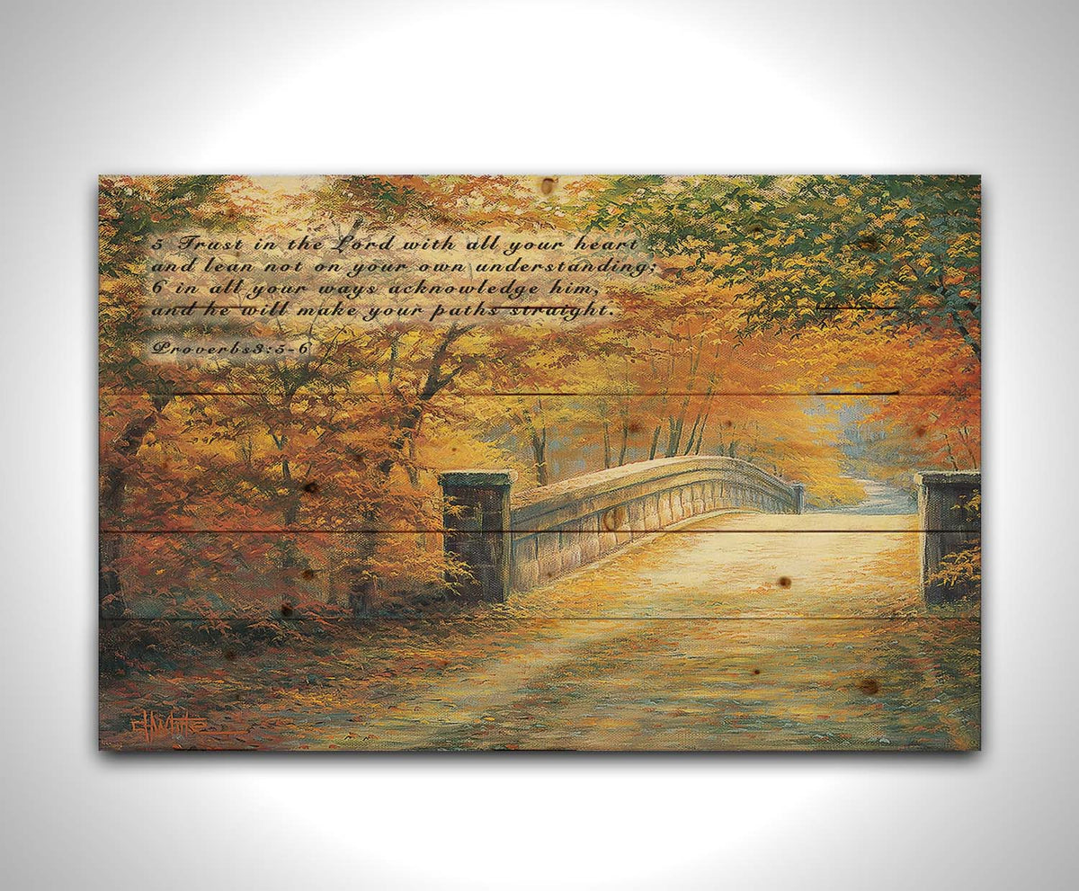 A painting looking down a bridge road during fall. The trees lining the road have turned yellow and orange for autumn, and some of their fallen leaves are scatted along the path. It is overlaid in the upper left with Proverbs 3:5-6 of the Bible, reading "5. Trust in the Lord with all your heart and lean not on your own understanding; 6. In all your ways acknowledge him, and he will make your paths straight." Printed on a wood pallet.
