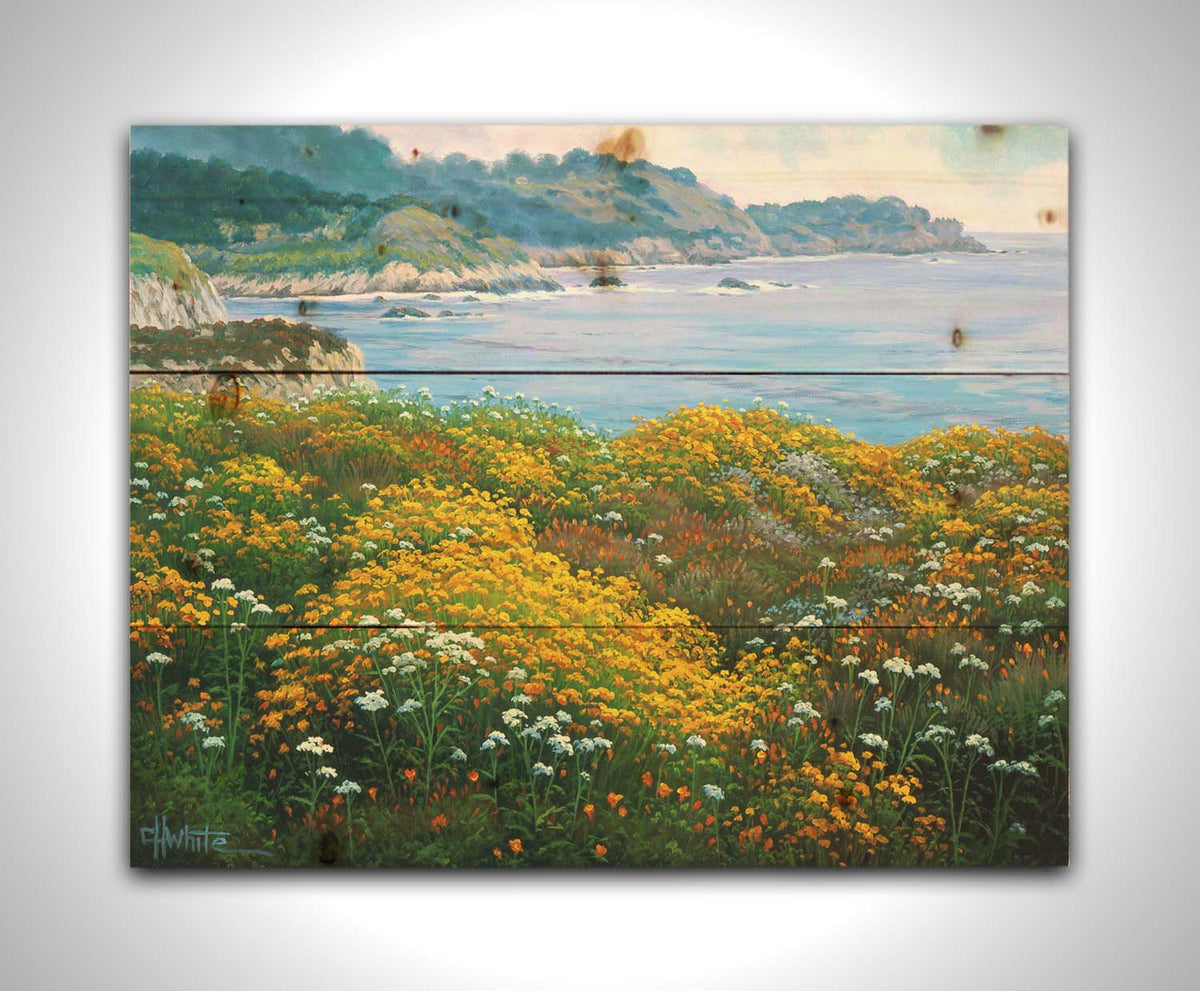 A painting of wildflowers growing in vibrant hues of yellow, white, orange, and blue, overlooking the sea from a cliff. Printed on a wood pallet.