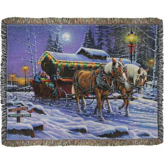 A woven throw blanket printed with a painting of people on a horse-drawn sleigh ride around a lake during Christmas.
