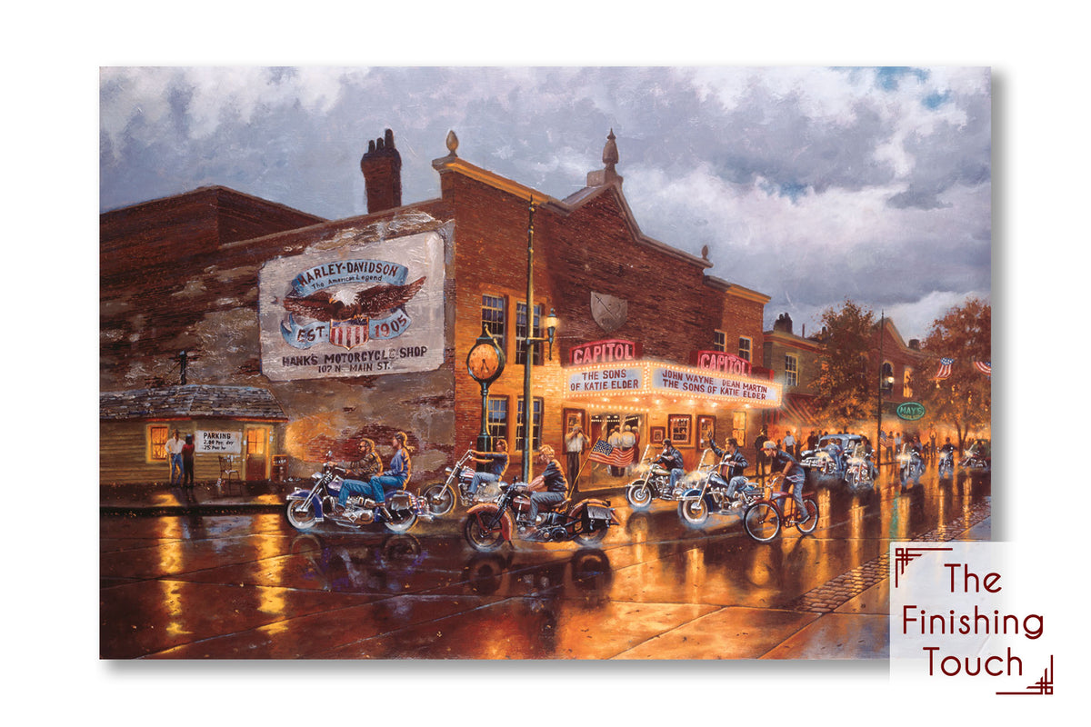 A painting of a group of bikers riding their motorcycles down a town road past a Harley Davidson motorcycle shop, a movie theater, and other shops. The sky is cloudy, and the shop lights reflect off the damp pavement.