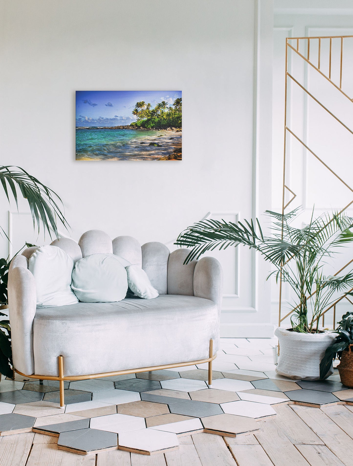 A photograph hanging on a wall. A photo of Laniākea beach. The water is a vibrant blue-green, and the stony beach circles around in the background where lush foliage and palm trees grow under a bright blue sky. Printed on canvas.