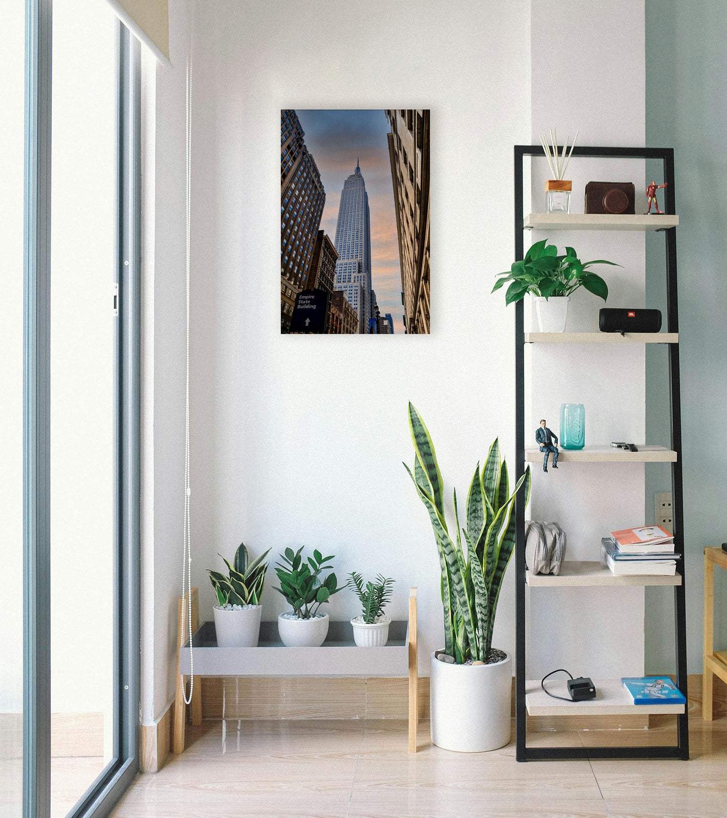 A photograph hanging on a wall. A photograph looking up at the Empire State Building in New York against a blue sky and orange clouds. Printed on canvas.