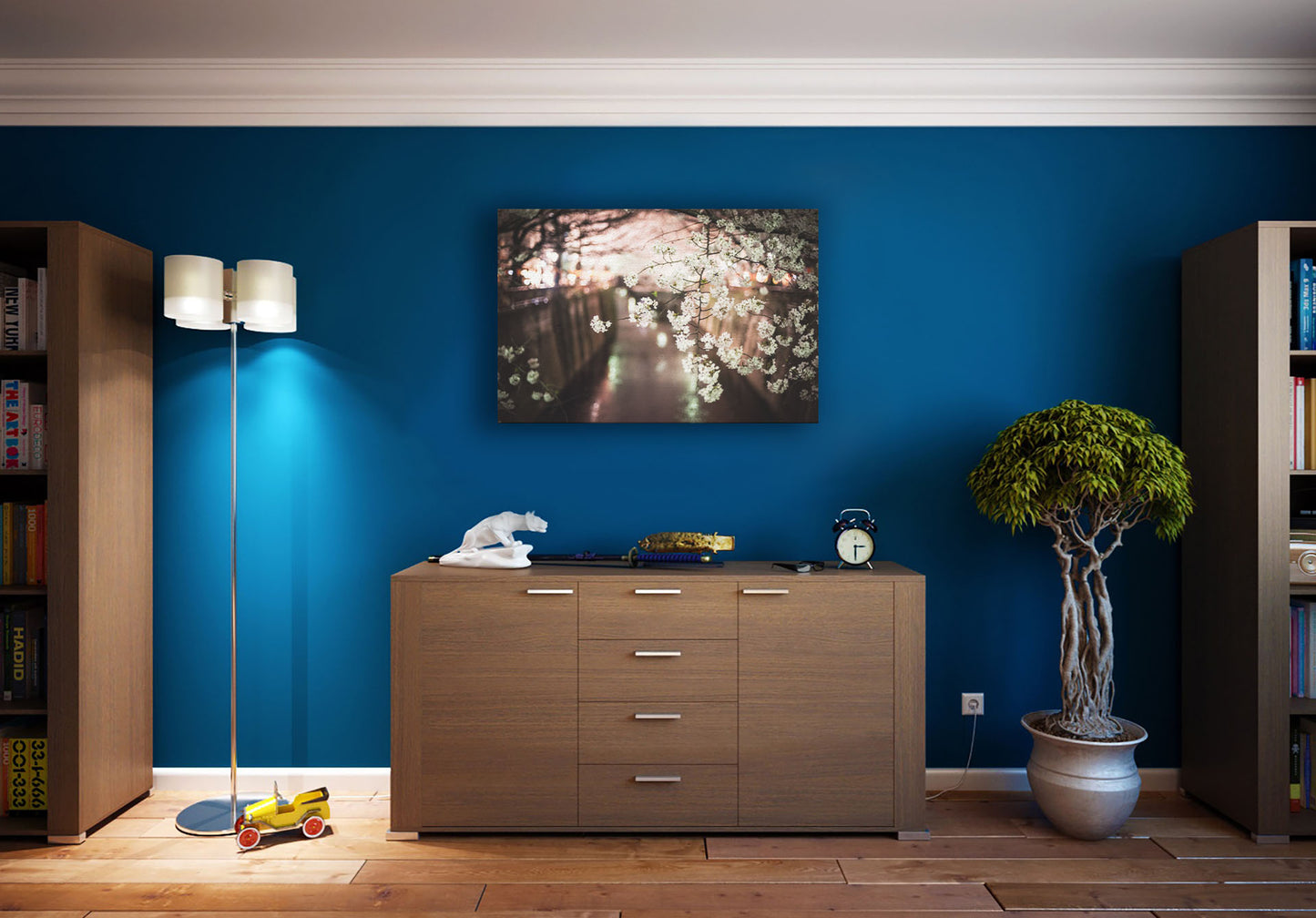 A photograph hanging on a study wall. A closeup photo of a branch of cherry blossoms, hanging over the Meguro River. Out of focus in the background, the river reflects twinkles of the city lights. Printed on canvas.