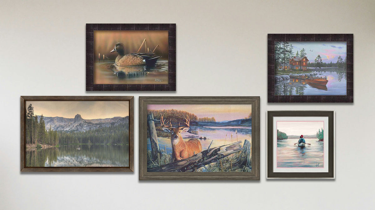 A collage of art in the designer By Dawn's Early Light package, including a framed painting of a deer standing in a lake at sunrise, a framed painting of a blue-winged teal swimming in a brown scene, a framed painting of a lakeside cabin and docked rowboat, a framed painting of a calm lake reflecting the low sun, and a matted and framed painting of people paddling a canoe across a lake on a peaceful, misty morning.