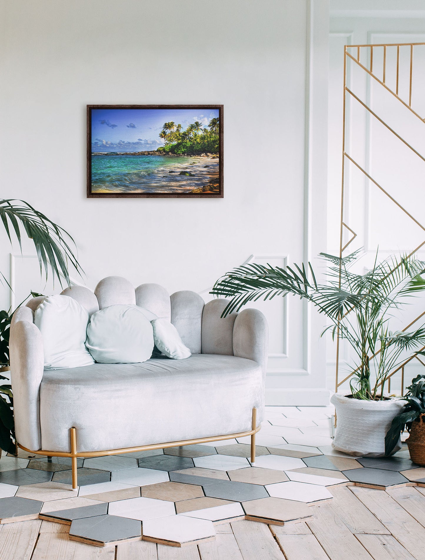 A photograph hanging on a wall. A photo of Laniākea beach. The water is a vibrant blue-green, and the stony beach circles around in the background where lush foliage and palm trees grow under a bright blue sky. Printed on canvas in a float frame.