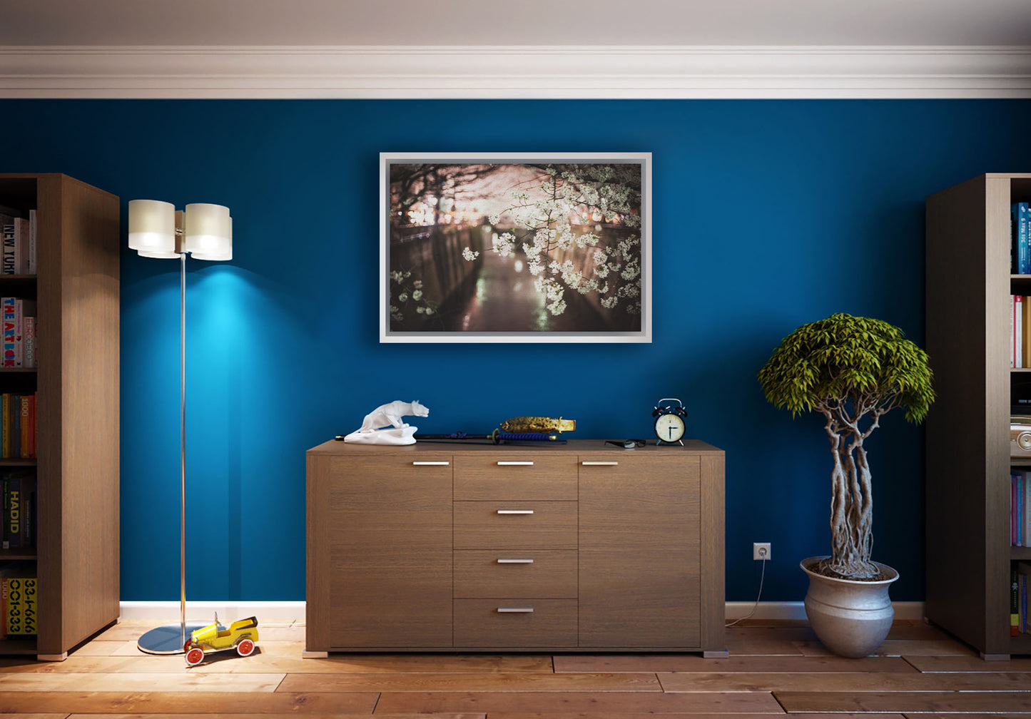 A photograph hanging on a study wall. A closeup photo of a branch of cherry blossoms, hanging over the Meguro River. Out of focus in the background, the river reflects twinkles of the city lights. Printed on canvas in a float frame.
