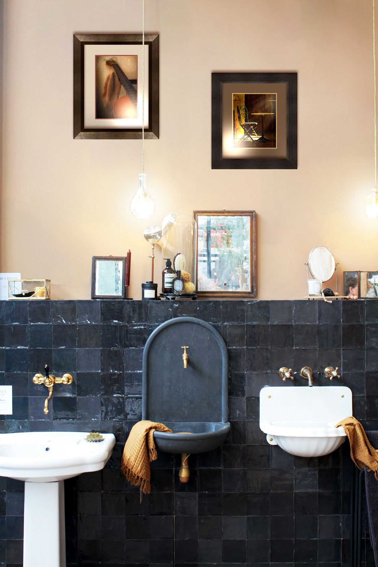 Two photographs hanging on a bathroom wall. The first is a photo of an acoustic guitar and a hat, sitting on a chair. Printed on paper, matted, and framed. The second is a photo of chairs around a small table, illuminated by light pouring in through the window. Printed on paper, matted, and framed.