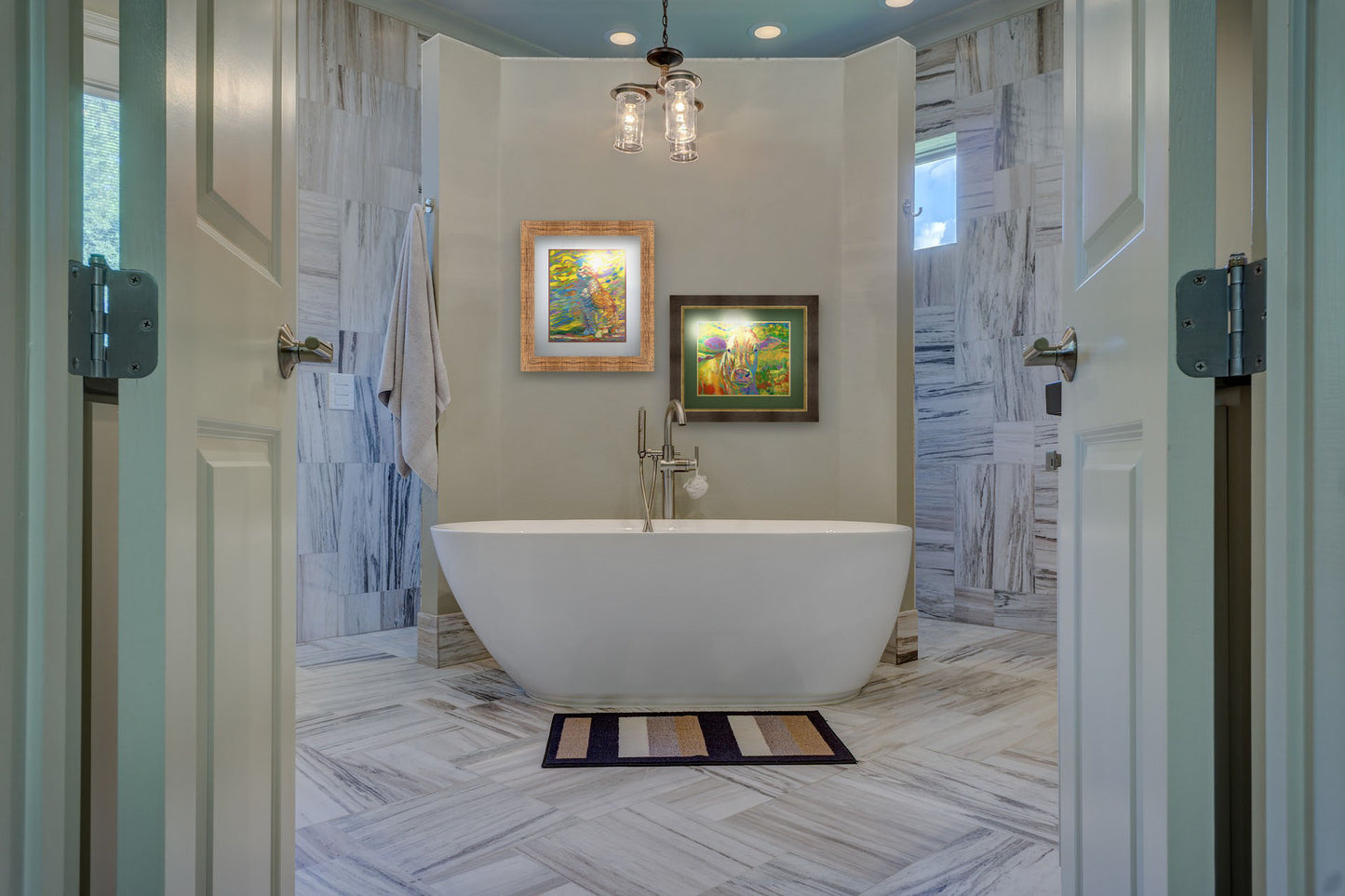 Two paintings hanging on a bathroom wall. The first is a painting of a cat done in broken color. The cat is sitting in a colorful environment and is composed of arbitrary color. Printed on paper, matted, and framed. The second is a painting of a cow standing in a pasture. It is painted in arbitrary colors, using a broad spectrum of bright colors from red through purple. Printed on paper, matted, and framed.