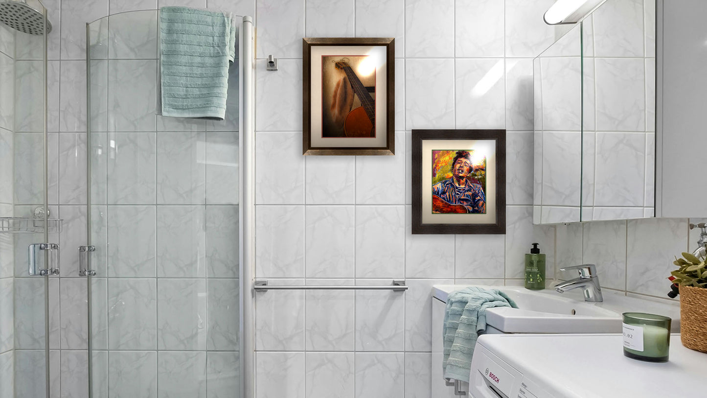 A photograph and a painting hanging on a bathroom wall. The first is a photo of an acoustic guitar and a hat, sitting on a chair. Printed on paper, matted, and framed. The second is a portrait painting of highly acclaimed singer-songwriter Bob Dylan. The musician is painted in a broken color style that brings the piece to life. Printed on paper, matted, and framed.
