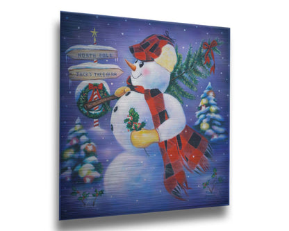 A painting of a snowman carrying a small Christmas tree, holding holly. It is standing by a sign indicating that it is taking the tree from Jack's Tree Farm to the North Pole. Printed on metal.