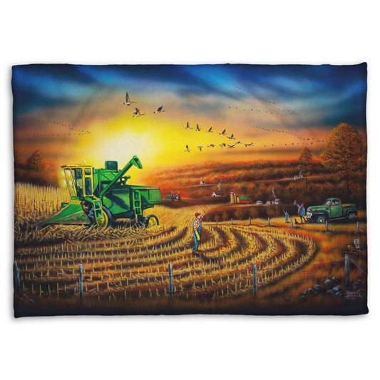 Coral fleece blanket with a scenic design of a farm landscape, with a harvester stopped in a partially harvested field of corn.