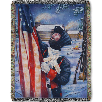Woven blanket designed with a soldier holding an American flag in a snowy landscape.