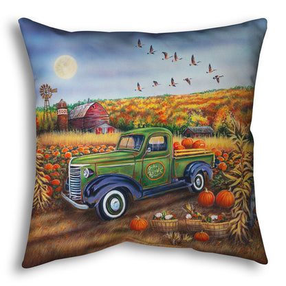 A throw pillow designed with a painting of a farm, featuring a field of pumpkins and a field of corn. There is a forest of yellow, orange, red, and green fall trees in the background, and geese fly overhead.