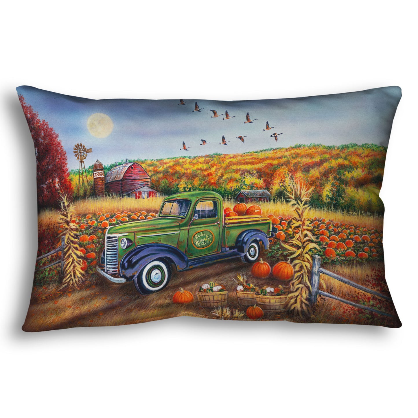 A throw pillow designed with a painting of a farm, featuring a field of pumpkins and a field of corn. There is a forest of yellow, orange, red, and green fall trees in the background, and geese fly overhead.