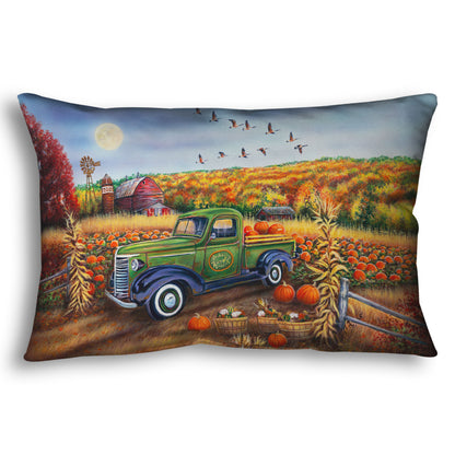A throw pillow designed with a painting of a farm, featuring a field of pumpkins and a field of corn. There is a forest of yellow, orange, red, and green fall trees in the background, and geese fly overhead.