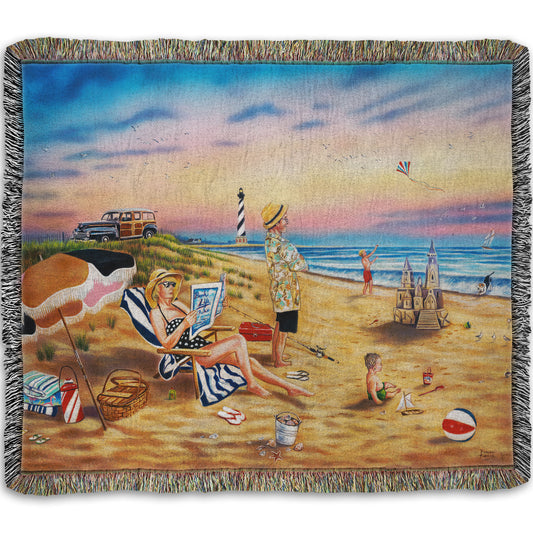 A woven throw blanket designed with a painting of a family vacationing on the beach. The adults relax while the children play, with one in the sand and another flying a kite with their dog.