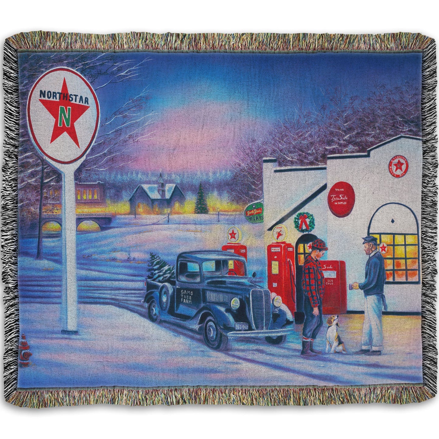 A woven throw blanket decorated with a 1950s Americana scene, with a vintage truck refueling at a Northstar gas station.