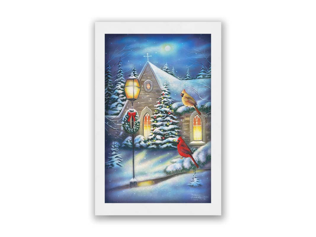 A painting of cardinals perched on evergreen branches on a snowy night, in front of a church decorated for Christmas. Printed on canvas and framed.