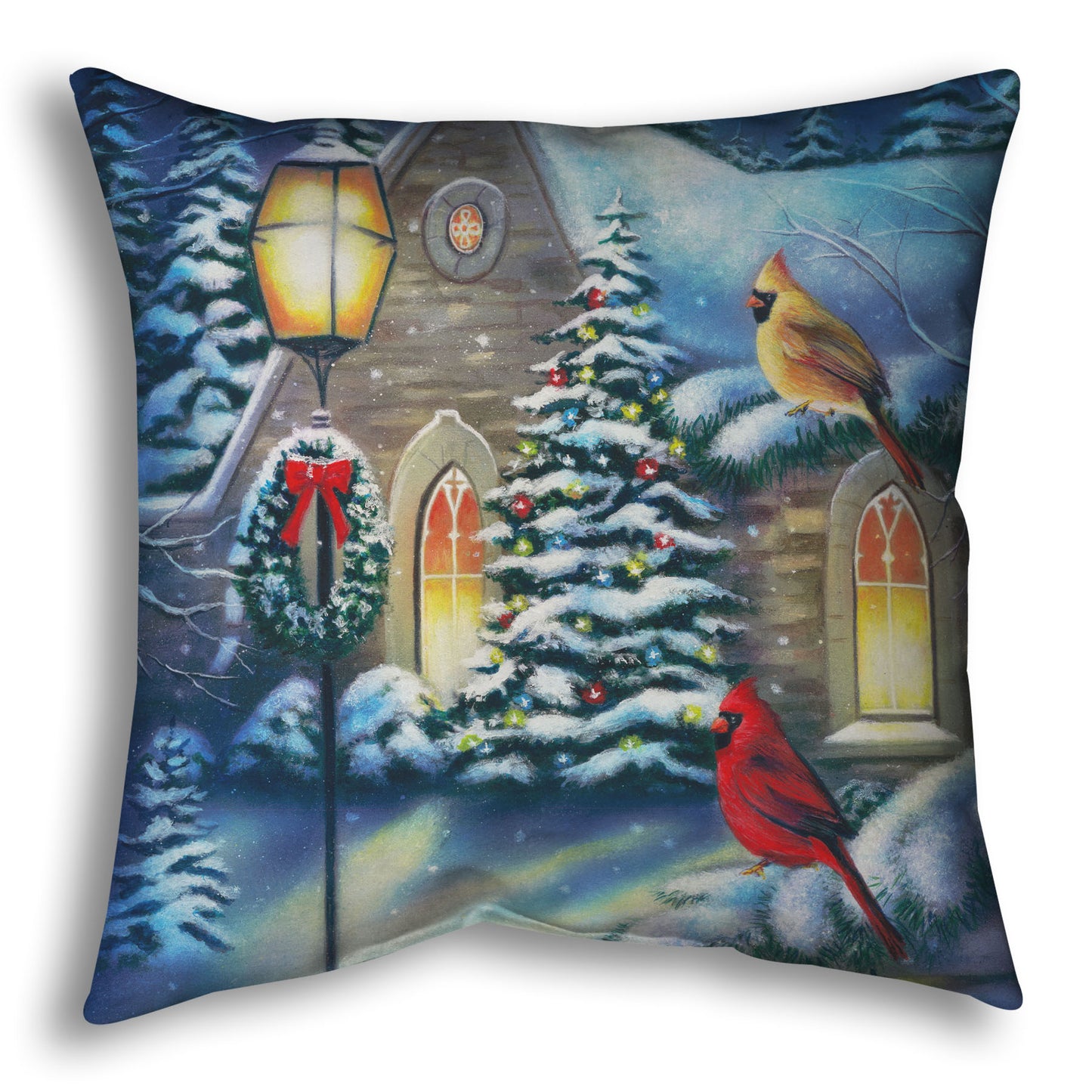 Throw pillow designed with a snowy christmas scene in a church courtyard, where cardinals are perched on evergreen tree branches.