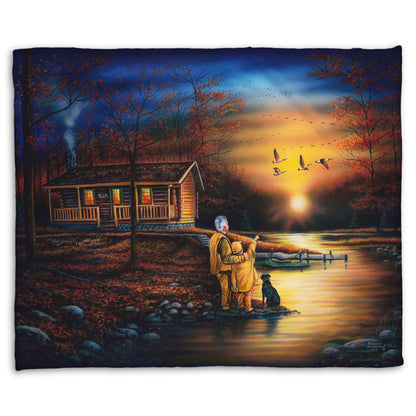 A coral fleece throw blanket designed with a painting of a man and a child standing by a river and cabin. They are watching geese fly overhead at sunset.