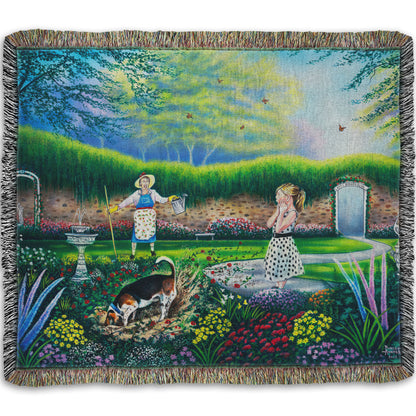 A woven throw blanket designed with a painting of a beautiful garden, but a dog is digging up the rose bushes, ruining them. The woman gardening and a child are looking on in shock.