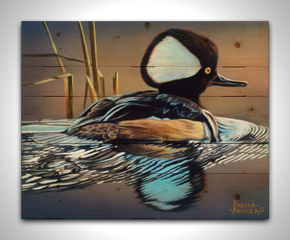 A painting of a hooded merganser duck, floating on the water with its reflection rippling below. Printed on a wood pallet.