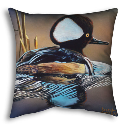A throw pillow decorated with the design of a hooded merganser duck, floating on the water with its reflection rippling below.