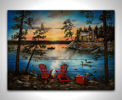 A painting of a lake at sunset, with a campfire in the foreground. Two loons drift across the water, as well as two fishers. Printed on a wood pallet.