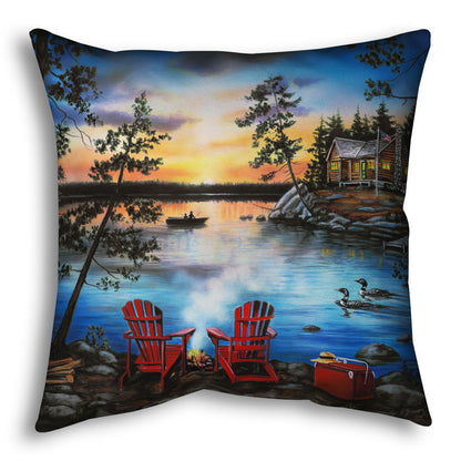 A throw pillow designed after a painting of a lake at sunset, with a campfire in the foreground. Two loons drift across the water, as well as two fishers.