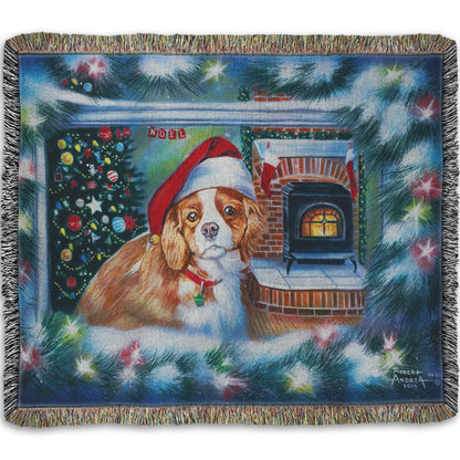 A woven throw blanket depicting a little dog with a red santa hat, sitting inside near a fireplace.