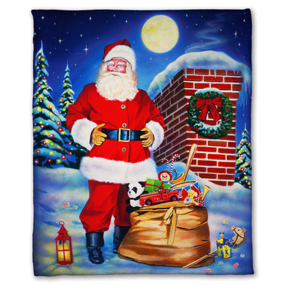 Festive blanket with a Santa Claus design. He stands on a snowy rooftop at night with a bag of toys.