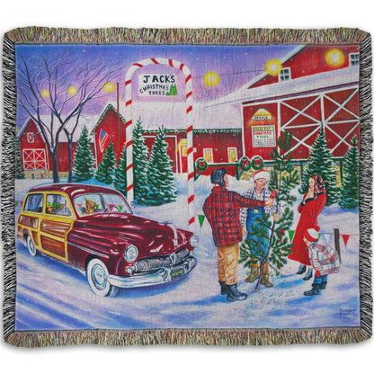 Woven throw blanket detailed with a painting of a family at a farm, buying a christmas tree.
