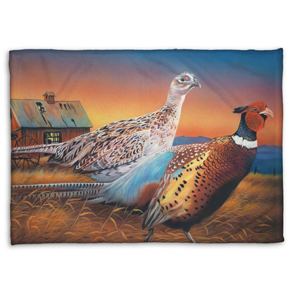 Coral fleece blanket designed with a painting of two pheasants, walking through golden grasses against a colorful sunset.