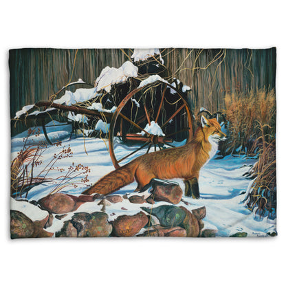 A coral fleece throw blanket designed with a painting of a red fox in the winter snow. It is standing by some old farming equipment, grasses, and stones.